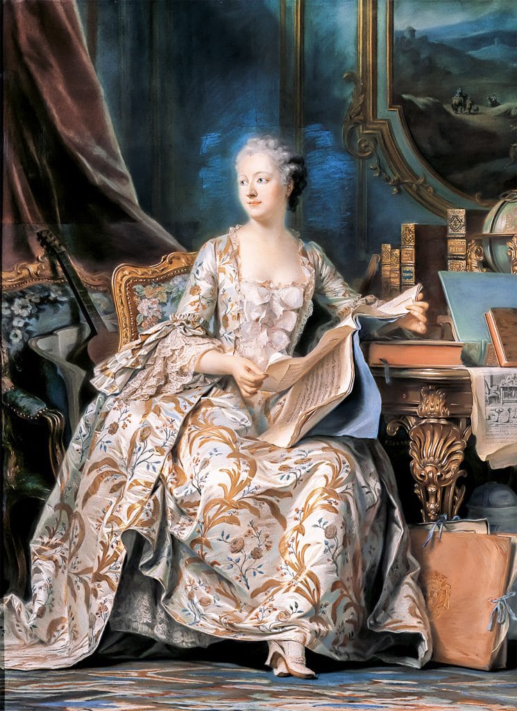 A poised woman in an elaborate brocade gown sits at her writing desk surrounded by books, globes, and fine furniture. She holds a letter with a calm, intellectual air. The backdrop includes a grand mirror and elegant Rococo decor.