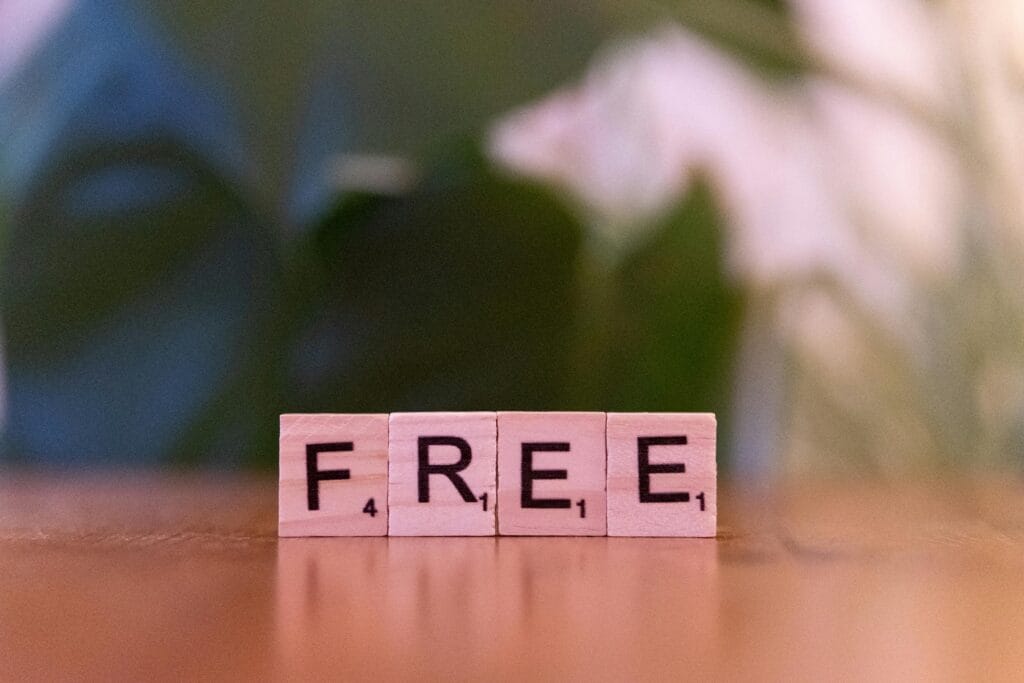 Featuring Free Spot the Difference. Four wooden Scrabble tiles spelling the word “FREE” placed on a table with a soft-focus green background. Featuring 
