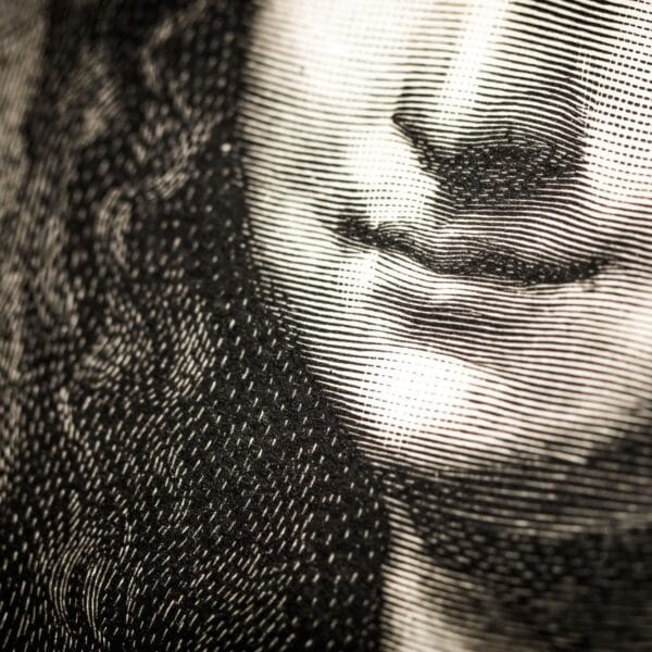 Close-up of an engraving showing the lower half of a person's face. Intricate lines create a textured, vintage look, highlighting a subtle smile.